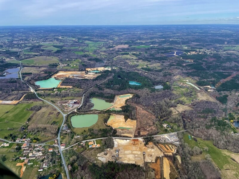 Vue aérienne d'une ville avec toits rouges et rues sous un ciel bleu lumineux, lors d'un baptême en hélicoptère dans le Limousin.
