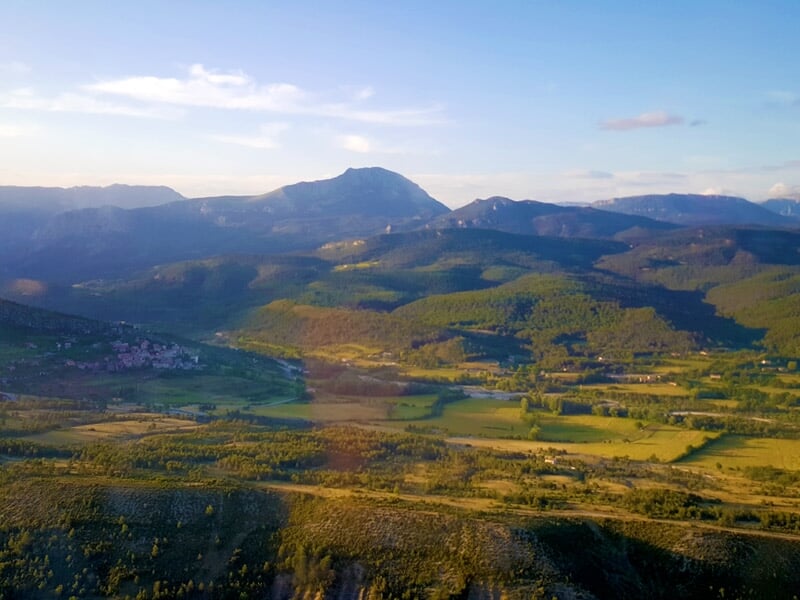 Montagnes enneigées avec un lac gelé visible au centre sous un ciel bleu clair.