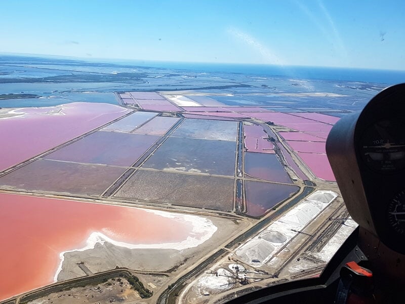 Vue aérienne depuis un hélicoptère des bassins colorés de salines près de Nîmes, avec le tableau de bord visible.