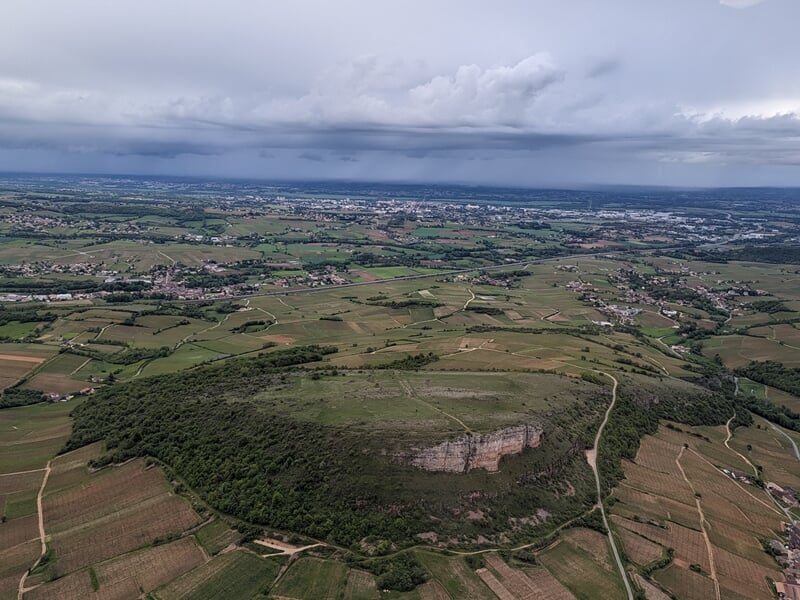 Vue aérienne d'un paysage rural avec collines, champs cultivés et un ciel nuageux, lors d'un vol en hélicoptère au-dessus du Morvan.