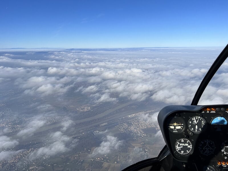 Vue aérienne d'une étendue de nuages et de paysages urbains capturée depuis un hélicoptère.