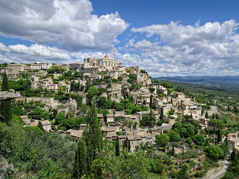 Village perché de Gordes, avec ses maisons en pierre et sa végétation luxuriante, surplombant la vallée.