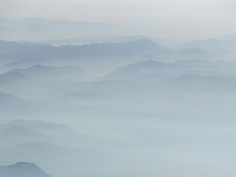 Paysage de montagnes embrumées avec des reliefs successifs.