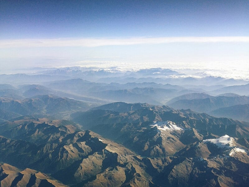 Panorama de montagnes avec des sommets et des vallées éclairés par le soleil.