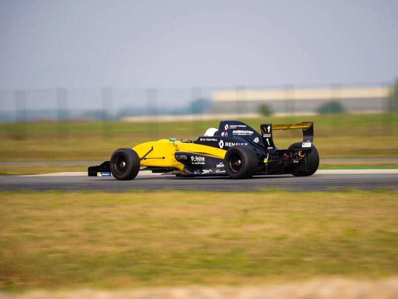 Une monoplace jaune en mouvement rapide sur une piste de course, avec un effet de flou de mouvement soulignant la vitesse de la voiture