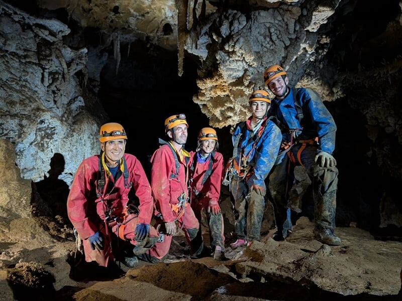 Groupe de cinq spéléologues équipés de casques et combinaisons dans une grotte rocheuse à Beaumont-de-Pertuis.