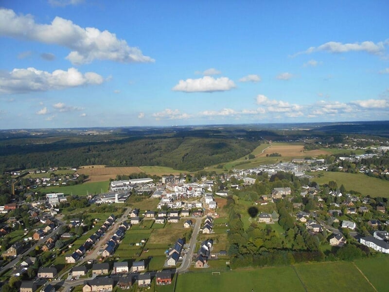 Paysage rural avec maisons, champs et forêts vus depuis une montgolfière en vol.