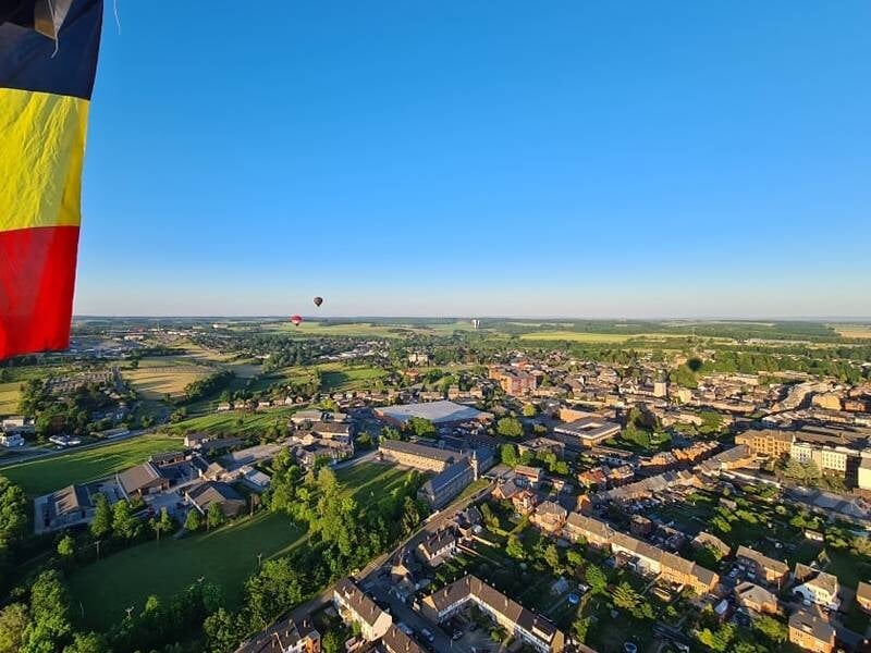 Vue panoramique d'une rivière sinueuse traversant une ville entourée de collines boisées.
