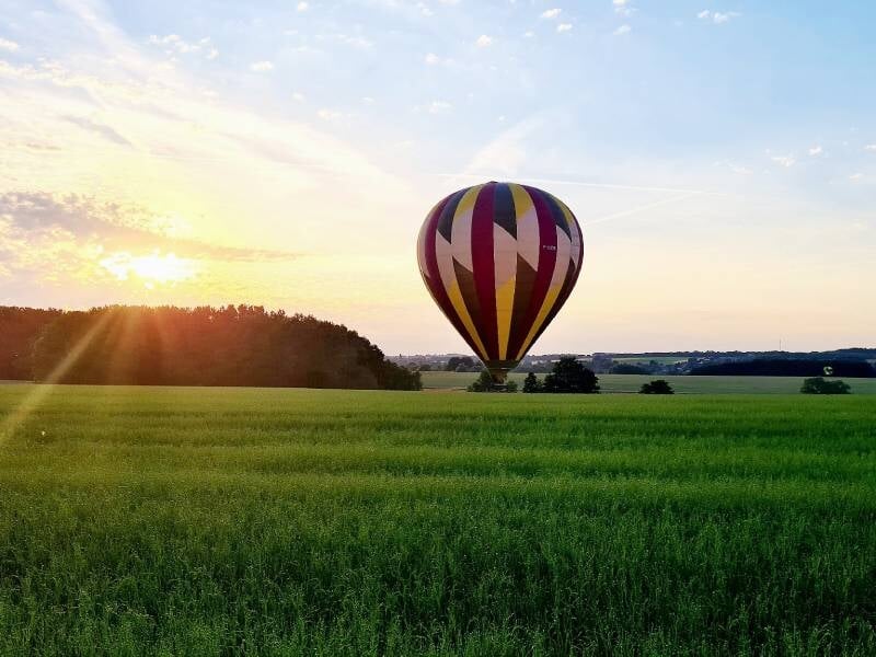 Montgolfière multicolore vue de dessous, flottant dans un ciel bleu clair au-dessus d'une ville.