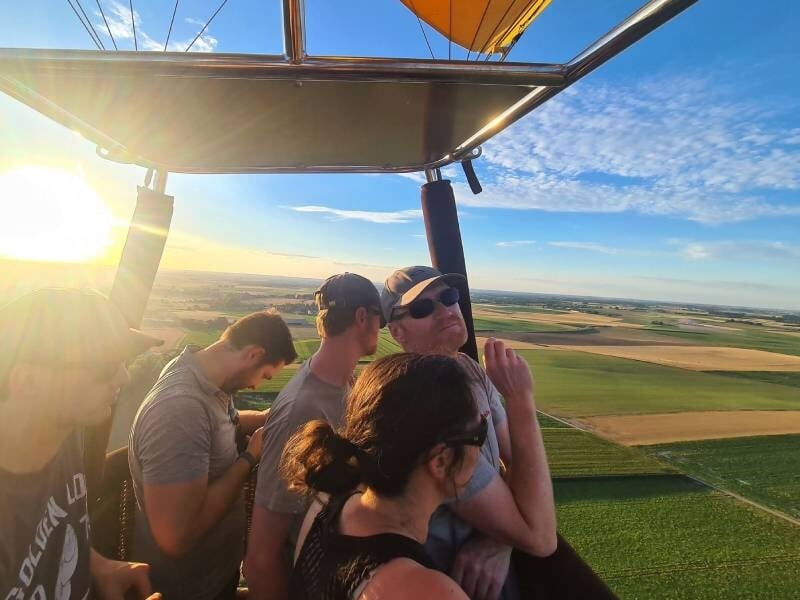 Ombre d'une montgolfière projetée sur un champ cultivé avec des chemins et des cultures.