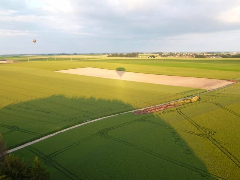Groupe de personnes dans une nacelle de montgolfière profitant d'un vol au-dessus des champs.