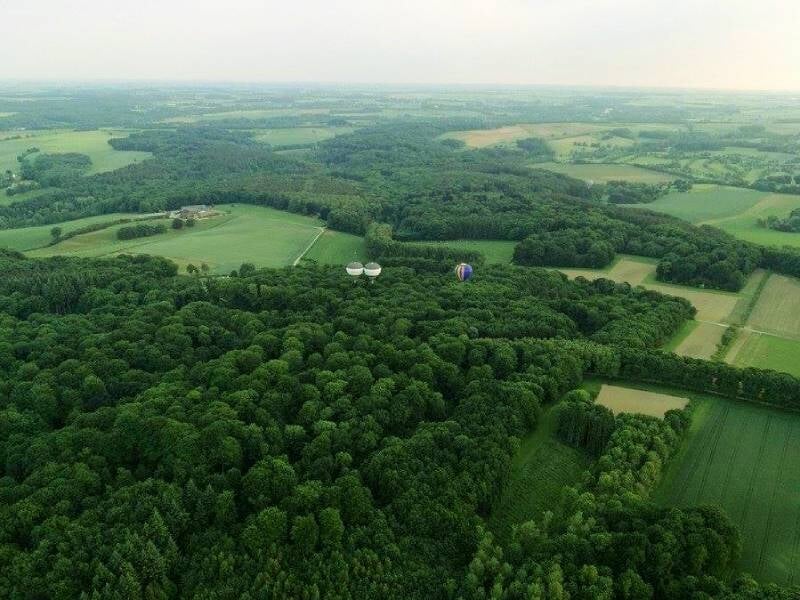 Montgolfière rouge, jaune et verte dégonflée sur un champ vert avec un homme assis à proximité.