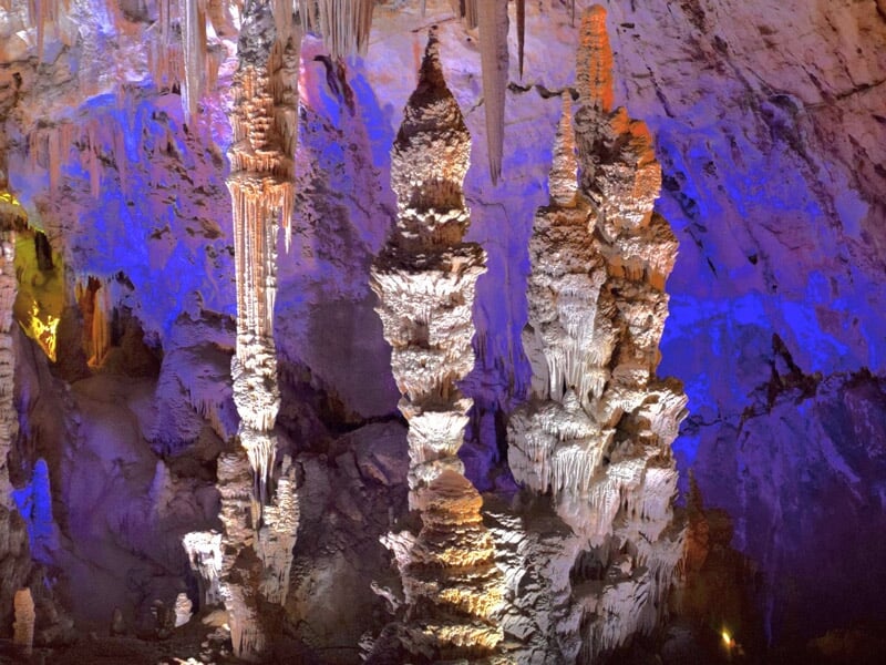Formation de stalactites et stalagmites éclairées en bleu et violet dans une grotte profonde