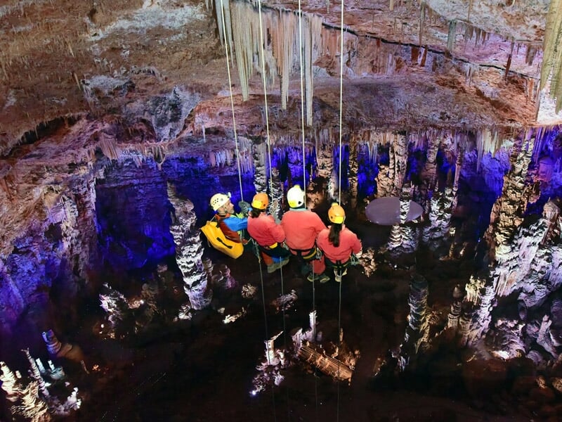 Groupe de spéléologues suspendus dans une grotte avec des casques et des cordes