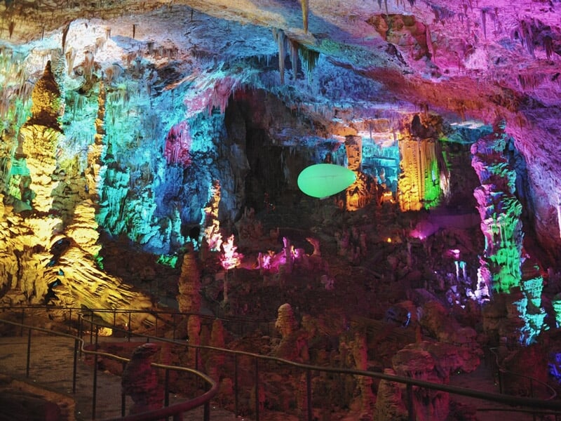 Intérieur d'une grotte illuminée de couleurs vives avec un ballon dirigeable suspendu