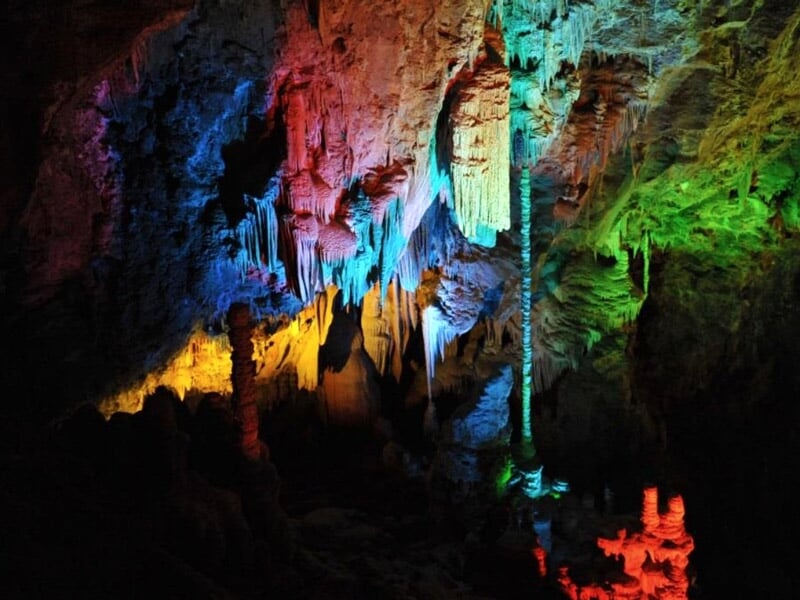 Grotte aux parois rocheuses éclairées par des lumières multicolores avec un ballon vert