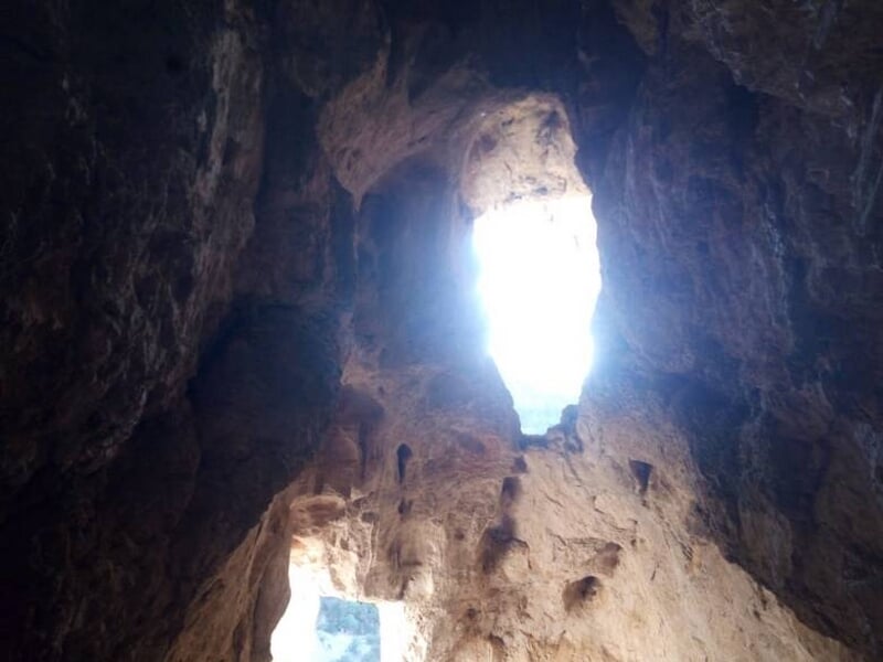 Entrée lumineuse d'une grotte vue de l'intérieur avec des parois rocheuses et lumière naturelle.