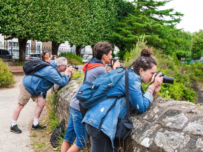 Groupe de trois personnes photographiant un paysage naturel depuis un point de vue en ville.