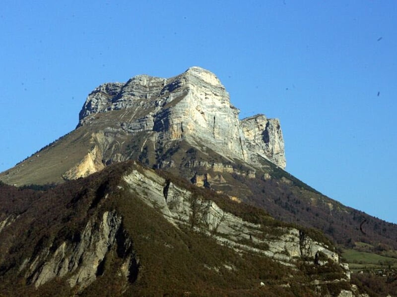 Vue extérieure d'une montagne rocheuse imposante sous un ciel bleu clair sans nuages.