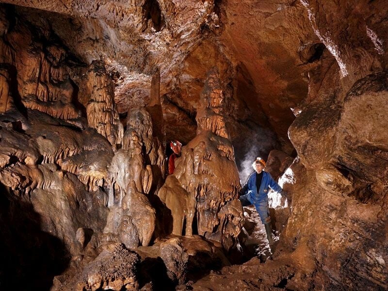 Exploration spéléologique dans une grotte avec des formations rocheuses impressionnantes et deux spéléologues en tenue.