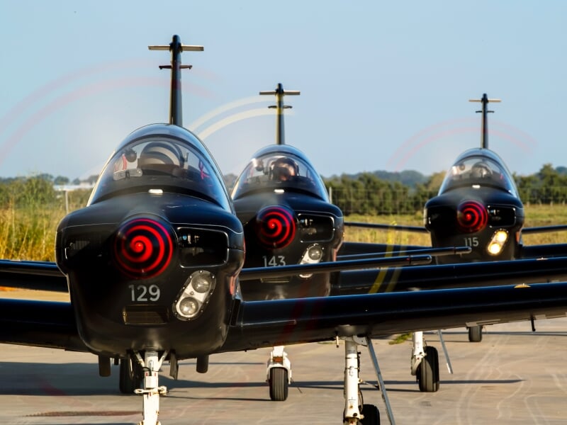 Alignement de trois avions d'entraînement militaires sur le tarmac, prêts pour un exercice de vol
