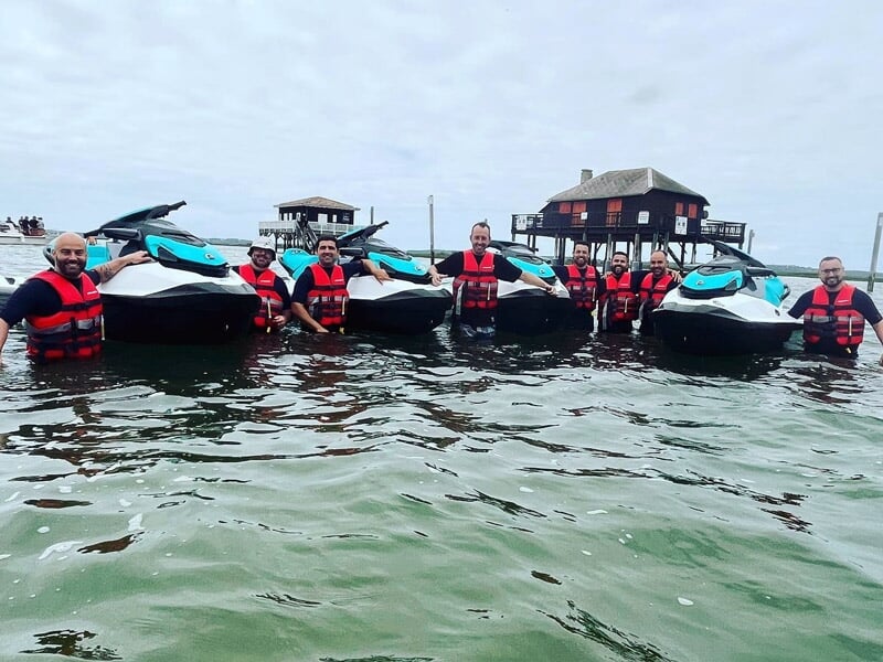 Groupe de personnes en gilets de sauvetage rouges posant dans l'eau avec plusieurs jetskis Sea-Doo à Arcachon.