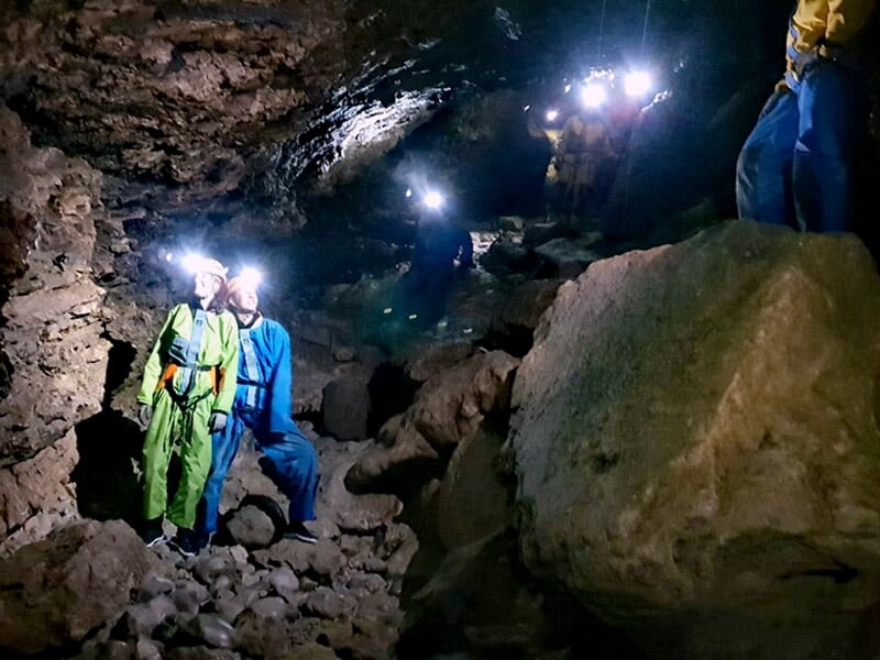 Gros plan sur des mains touchant une formation rocheuse naturelle dans une cavité souterraine.
