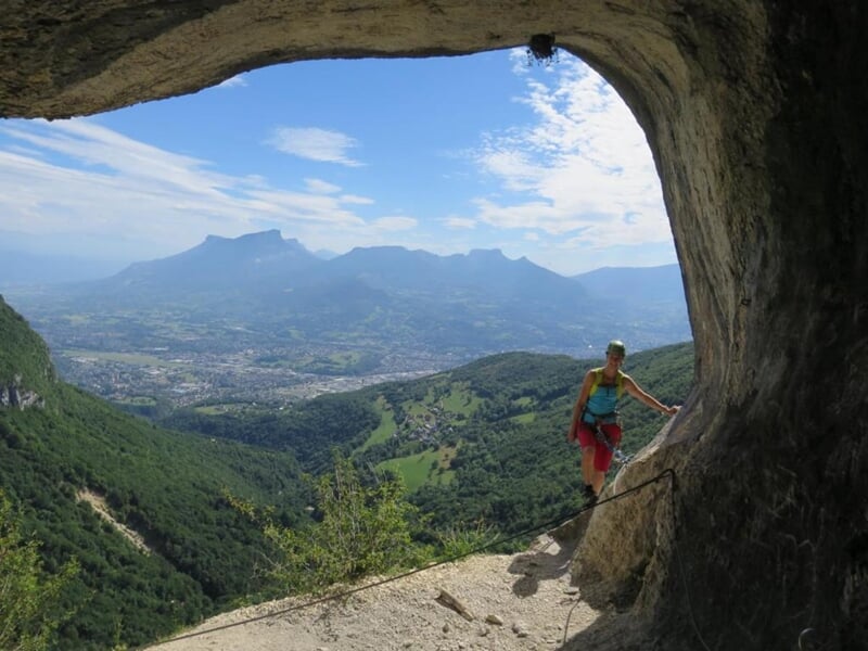 Gros plan d'une personne en casque descendant en rappel une cascade dans un canyon rocheux avec eau en bas.