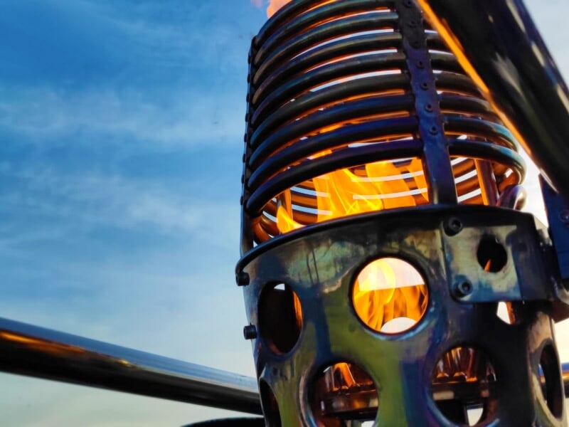 Gros plan sur la flamme d'un brûleur de montgolfière avec un ciel bleu en arrière-plan.