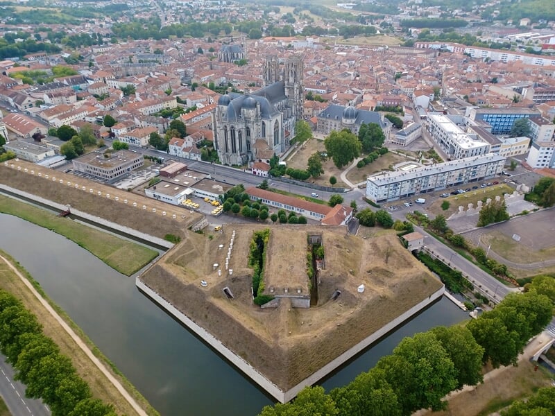 Vue aérienne d'une ville fortifiée avec un canal et des bâtiments historiques.