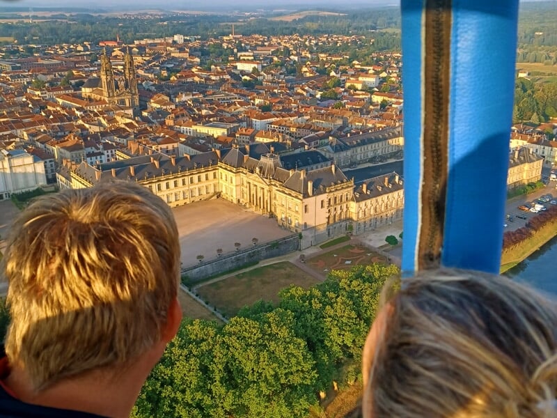 Personne debout à côté d'une montgolfière dégonflée au coucher du soleil dans un champ.