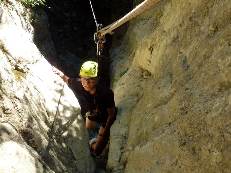 Personne en casque jaune grimpe une paroi rocheuse abrupte équipée d'une via ferrata en pleine nature.