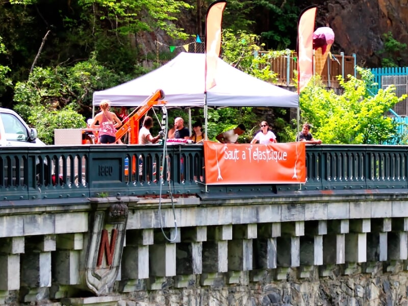Foule rassemblée sous une tente blanche avec une bannière orange pour un saut à l'élastique.