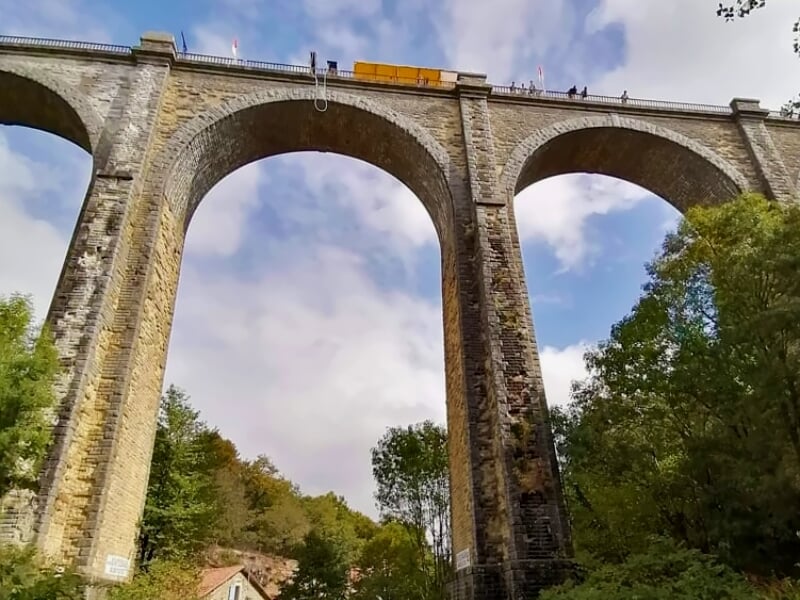 Viaduc en pierre vu de dessous avec plusieurs arches et un ciel nuageux.