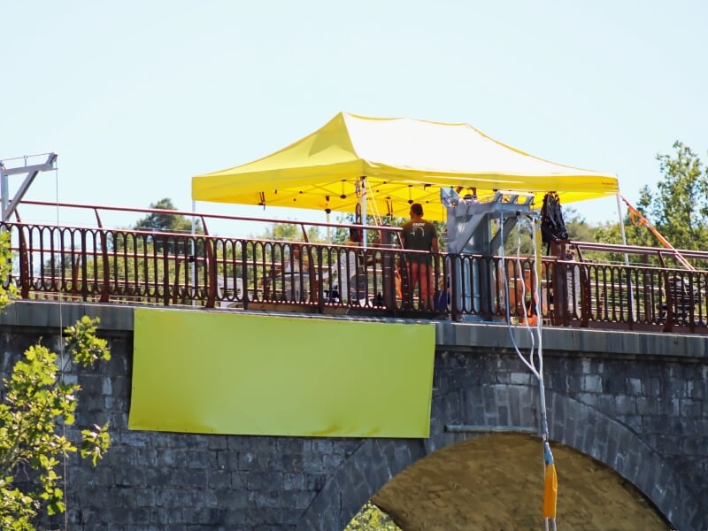 Personnes sur un pont avec une tente jaune et un équipement de saut à l'élastique.