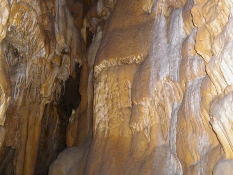 Paroi rocheuse intérieure d'une grotte avec formations calcaires aux teintes jaunes et brunes naturelles.