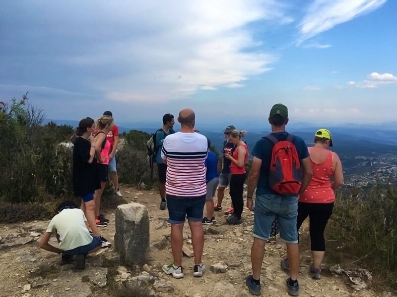 Groupe de personnes en randonnée sur un chemin de montagne avec vue panoramique sur la campagne.