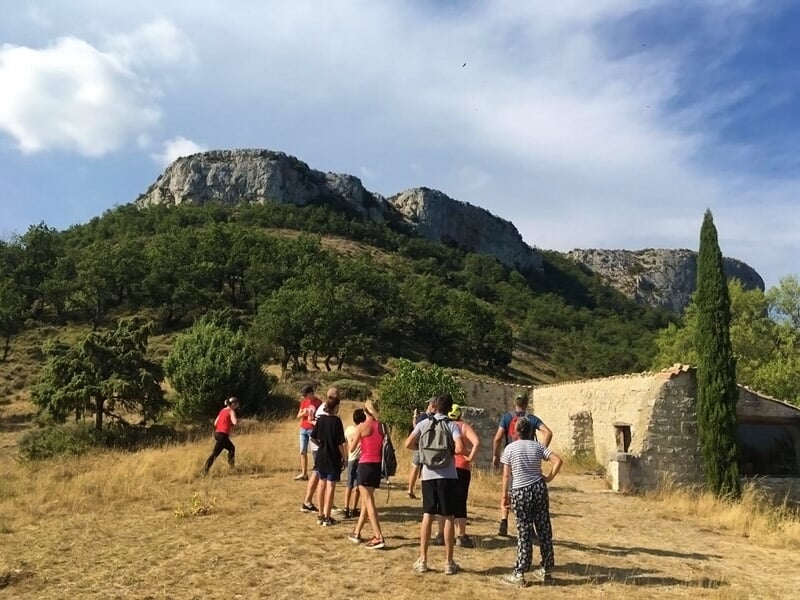 Randonneurs en groupe marchant vers un sommet rocheux sous un ciel clair et ensoleillé.