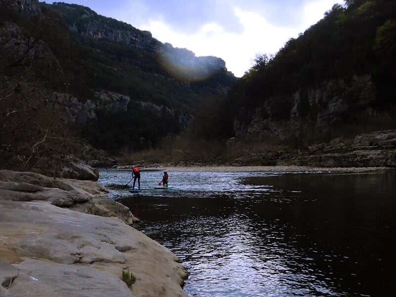 Vue aérienne d'une rivière sinueuse entourée de falaises et de forêts verdoyantes en Ardèche.