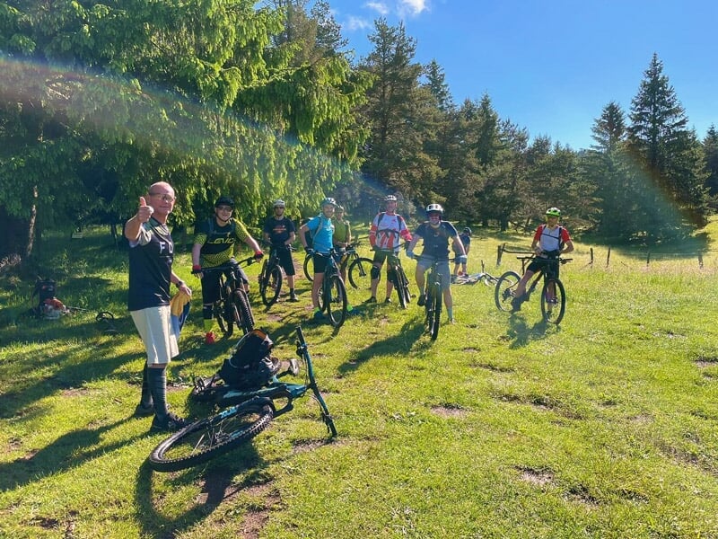 Groupe de cyclistes en pause sur un chemin forestier ensoleillé lors d'une sortie à vélo électrique.