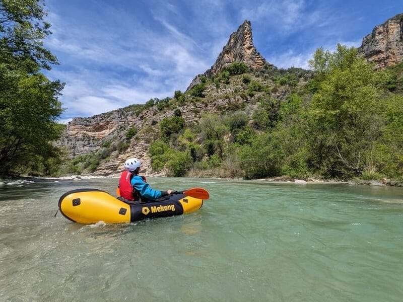Personne en kayak jaune sur une rivière calme entourée de falaises et de végétation lors d'une activité packraft à Vallon-Pont-D'Arc.