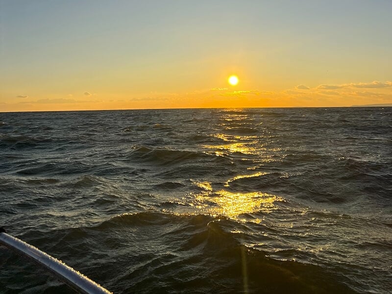 Coucher de soleil sur une mer agitée vu depuis un bateau.