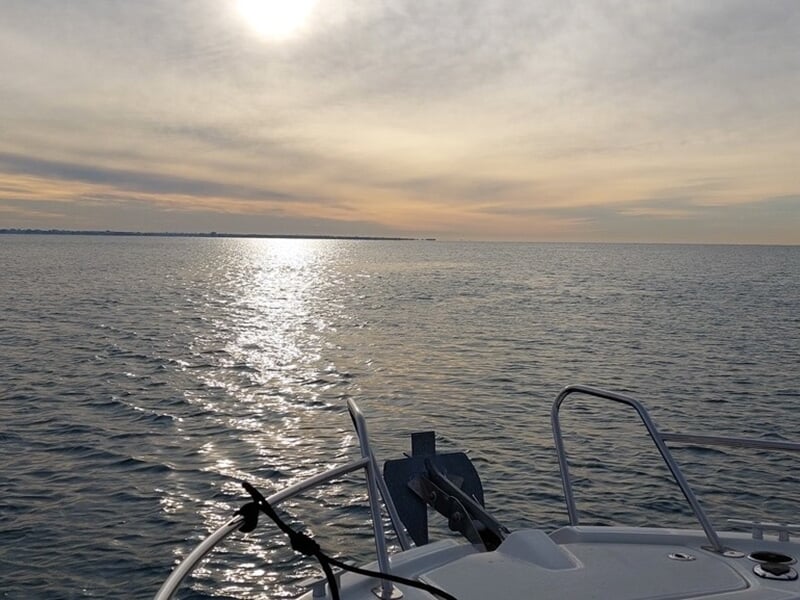 Lever ou coucher de soleil sur une mer calme, vu depuis l'avant d'un bateau.