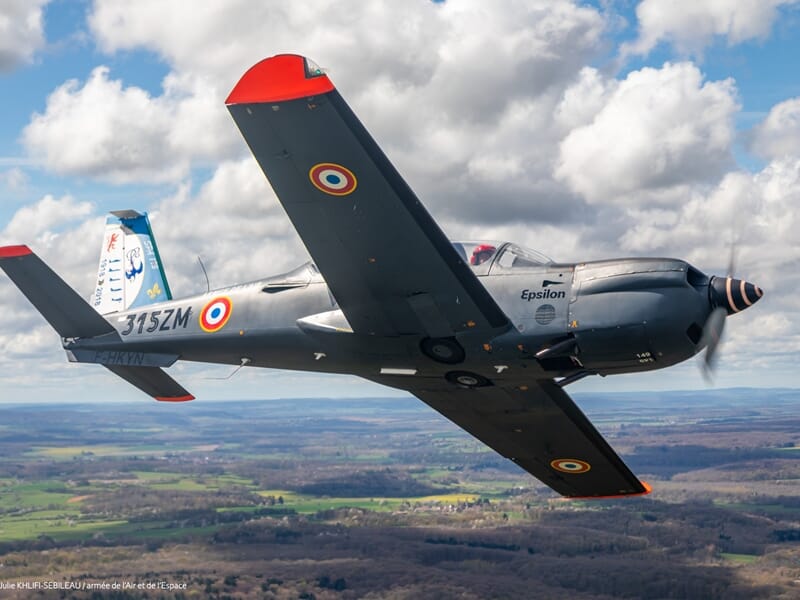 Avion militaire de chasse gris avec marquages français en vol au-dessus d'un paysage rural sous durant un baptême en avion d'entrainement militaire près de Paris