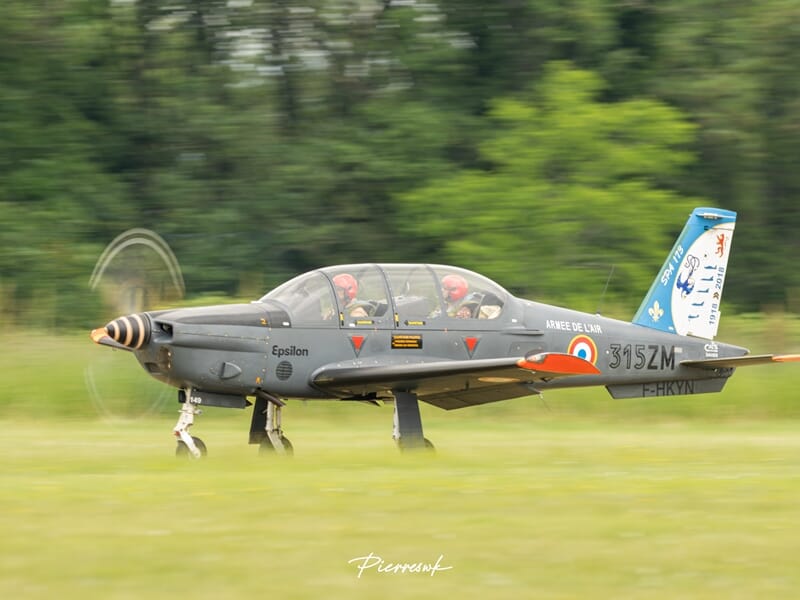 Avion de chasse gris au sol sur une piste herbeuse durant un baptême en avion d'entrainement militaire près de Paris