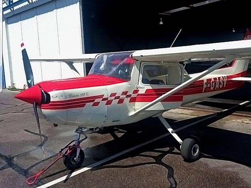 Petit avion blanc et rouge stationné devant un hangar, prêt pour une initiation au pilotage à l'aérodrome de Rouen.
