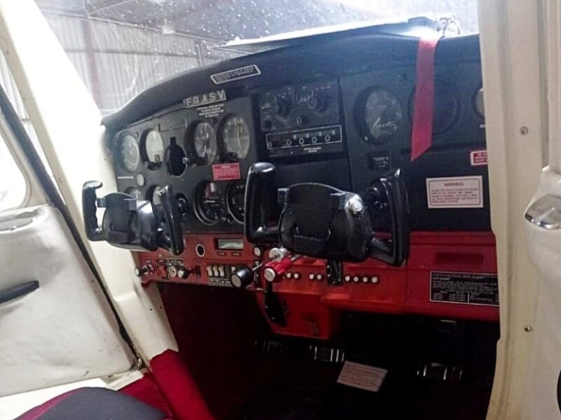 Tableau de bord d'un petit avion avec instruments de vol, volant double et commandes visibles dans le cockpit.