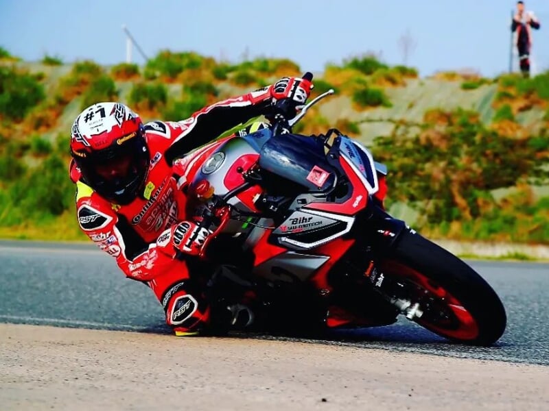 un pilote en combinaison rouge fait un virage serré sur une moto rouge sur un circuit de course