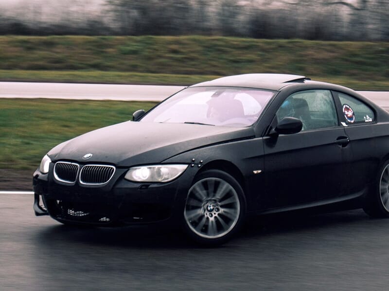 Une voiture BMW niore en train de drifter sur un circuit.