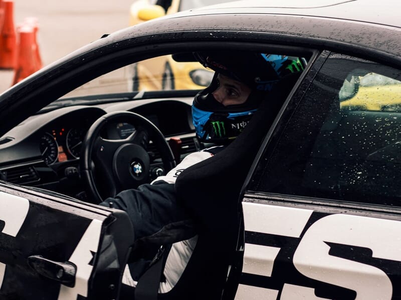 Un homme en tenue de pilote, assis dans une BMW noire, en train d'ouvrir la portière.